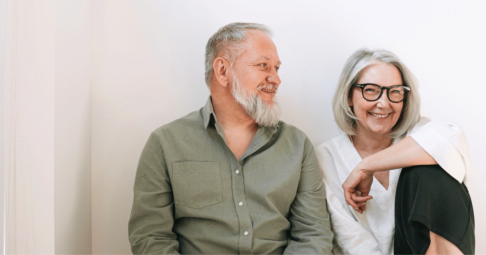 Joyful senior couple sitting together indoors, sharing smiles and love.