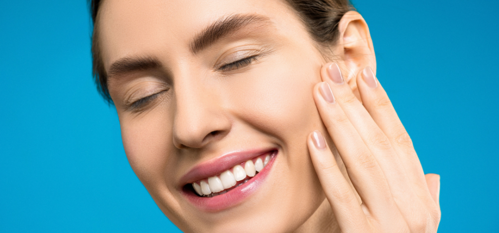 Portrait of a smiling woman with closed eyes against blue background.